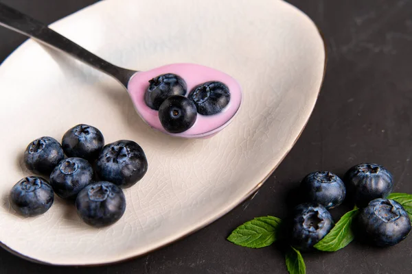 Sabroso yogur de arándano fresco agitar el postre en un tazón de cerámica de pie sobre fondo negro de mesa oscura . — Foto de Stock