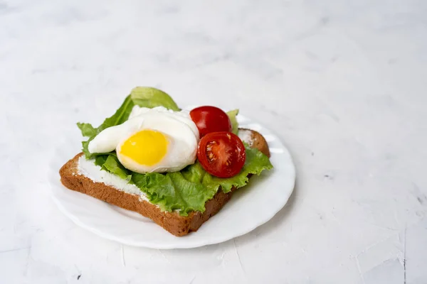 Sanduíche com salada de ovos fritos e tomate em uma placa branca em um fundo branco . — Fotografia de Stock