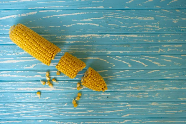 Corn cob with green leaves lies on table blue color background. — Stock Photo, Image