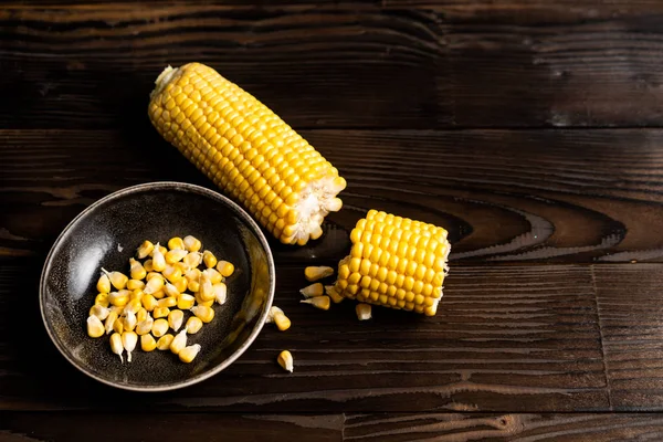 Corn cob with green leaves lies on table Dark wooden background. — Stock Photo, Image