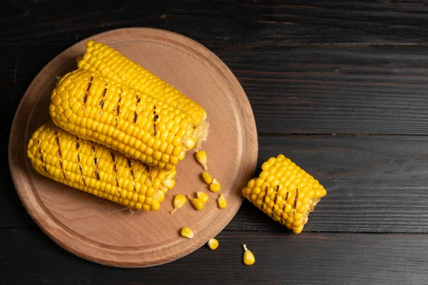 Grilled hot Corn cob lies on cutting board wooden table background. — Stock Photo, Image