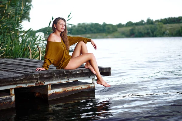 美しい白人の若い女の子は暖かい夏の日に川のピアスで思考に座っています — ストック写真