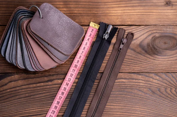 暗い木製のテーブルの靴とジッパー測定テープのための革のサンプル. — ストック写真