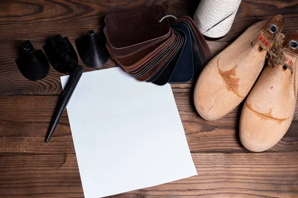 Campioni di pelle per scarpe e scarpe in legno durano sul tavolo di legno scuro. — Foto Stock