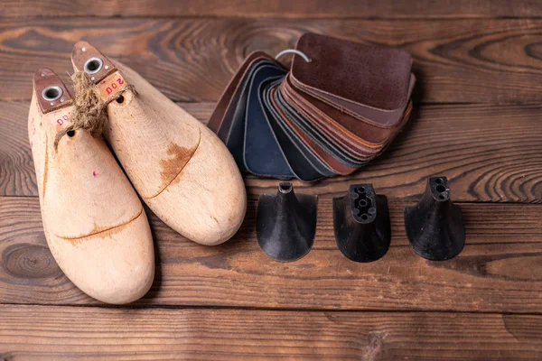 Échantillons en cuir pour chaussures et chaussures en bois dernier sur table en bois sombre. — Photo