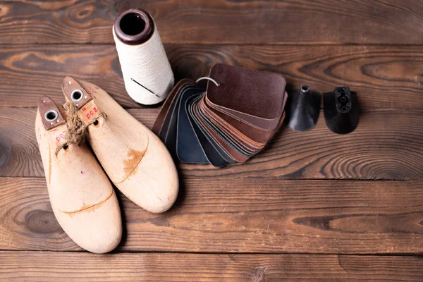 Échantillons en cuir pour chaussures et chaussures en bois dernier sur table en bois sombre. — Photo