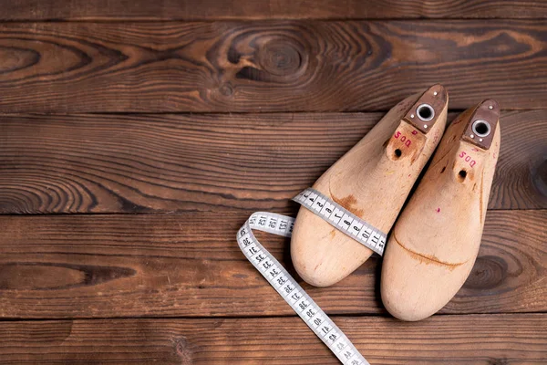 Leather samples for shoes and wooden shoe last on dark wooden table. — Stock Photo, Image