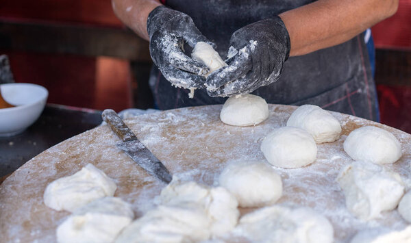 Chef in black gloves cuts raw dough into pieces make pizza Patties bread.