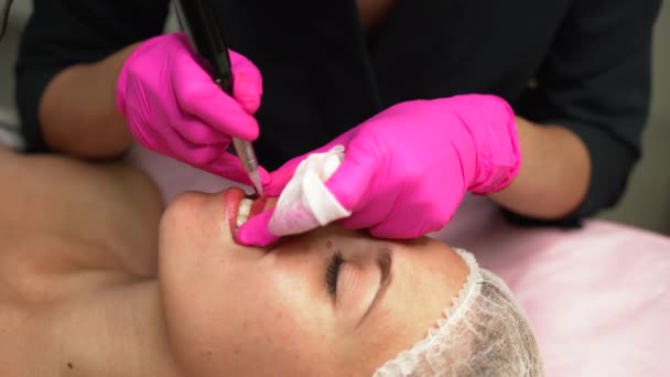 Doctor cosmetólogo hace procedimiento permanente maquillaje hembra cliente labios 4K — Vídeo de stock