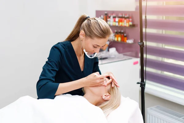 Cosmetologie kabinet klant ligt op de bank. Beautician brengt markering aan op wenkbrauwen. — Stockfoto