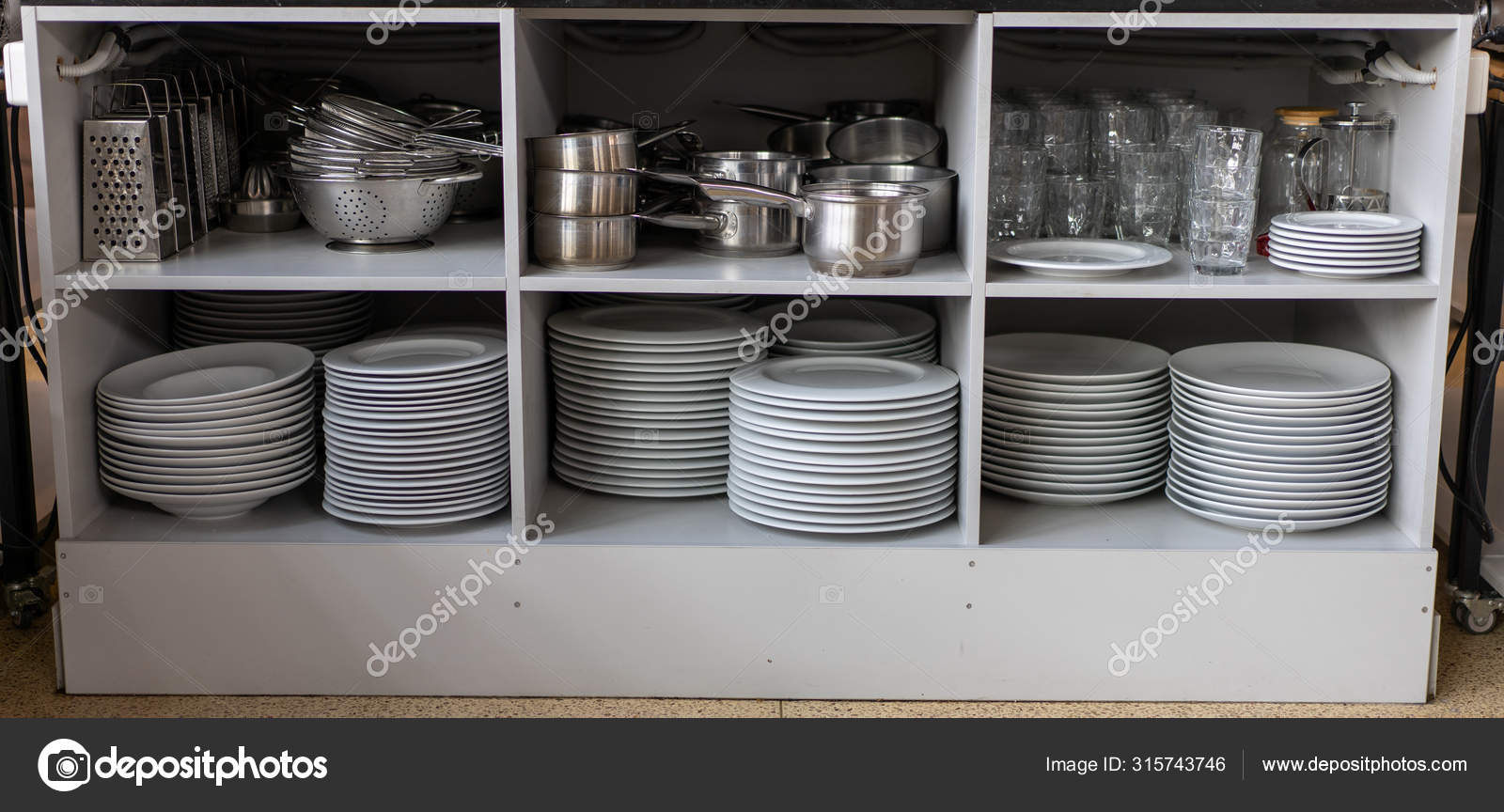 Stack white clean plates and other metal utensils on the shelves in commercial  restaurant. Stock Photo by ©andreonegin 315743746