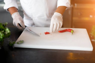 Tanımlanamayan genç Afrikalı şef restoranın profesyonel mutfağında duruyor et ve peynir sebzelerinden oluşan bir yemek hazırlıyor.. 