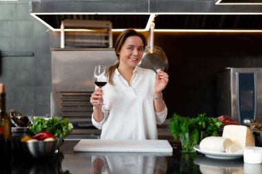 Beyaz üniformalı, güzel, beyaz bir kız. Kırmızı şarap içiyor ve gülümsüyor.