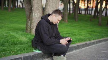 Elektronik kitap okuyan yakışıklı adam, e-kitap tableti okuyor, yaz günü halk parkında oturuyor, beyaz tenli erkek, elinde kitap tutuyor.