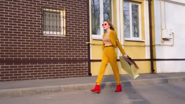 Une jeune fille européenne caucasienne Shopaholic marche le long de la rue avec des achats en paquets . — Video
