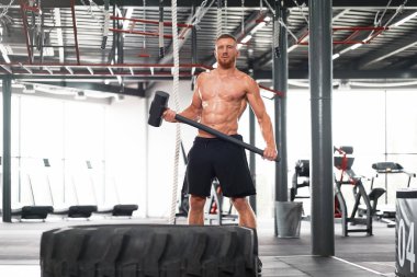 Erkek jimnastik çekici traktör tekerleğine çarptı. Büyük bir lastik sporcusuna çarptı. Orta yaşlı, yakışıklı vücut geliştirici, halterci. 