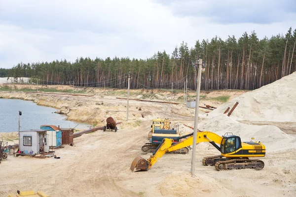 Sand quarry mining industry equipment excavator tractor standing sand land near lake water Industrial activity mine operation summer sunny day. Ecology problem Non-renewable resources of the Earth