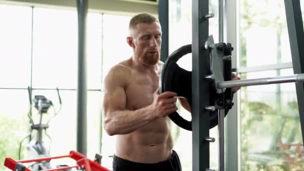 Ginásio homem barbell levantar pesos pratos máquina de exercício. Bonito atleta caucasiano treino — Vídeo de Stock