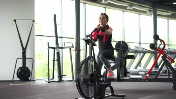 Mulher exercício bicicleta ginásio ciclismo aptidão. Fitness masculino usando ar bicicleta cardio treino . — Vídeo de Stock