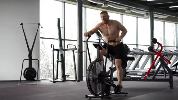 Man motionscykel gym cykling träning fitness. Fitness Man använder air bike cardio workout. — Stockvideo