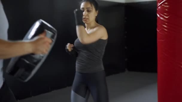 ボクシングのパーソナルトレーナーを訓練する女性。講師は女性ボクサーの戦闘練習を一緒に教える. — ストック動画