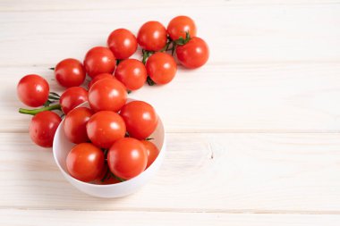 Beyaz ahşap masada kiraz domatesleri. Sulu olgun sebzeler. Sağlıklı beslenme. vejetaryen yemeği