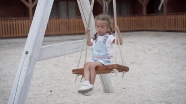 Oyuncu çocuk salıncak sallıyor. Neşeli küçük kız yaz tatilinde oyun oynuyor. 