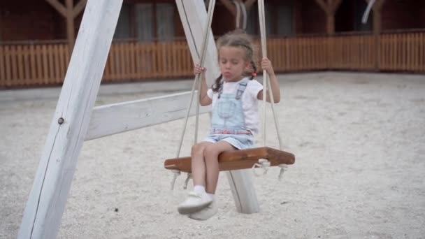 Oyuncu çocuk salıncak sallıyor. Neşeli küçük kız yaz tatilinde oyun oynuyor. — Stok video