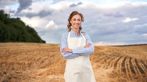女性農家エプロン立っ農地笑みを浮かべて女性農学者の専門農業ビジネス幸せな正の原因アジアの労働者の農業分野かわいい女の子の腕は曇った空の背景を越え — ストック写真