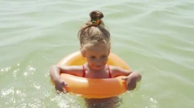 Çocuk şişme deniz halkası yüzüyor. Çocuk Yaşamı şamandırası. Küçük beyaz kız deniz suyunda iyi eğlenceler. Yaz tatili boş zamanlarında. Yaşam biçimi