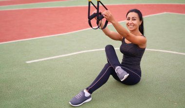 Trx spor sahası kullanan kız sporcu eğitimi. Karışık ırk genç yetişkin kadın spor süspansiyon sistemi. Açık havada esnemek için sağlıklı bir yaşam tarzı. Vücut makineni yap                            