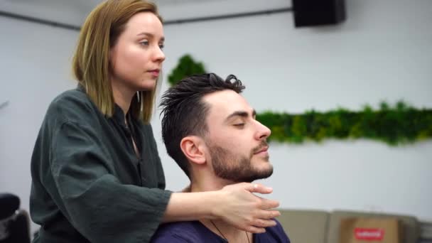 Handsome blue eyed man sitting in barber shop. Hairstylist Hairdresser Woman cutting his hair. Female barber. — Stock Video