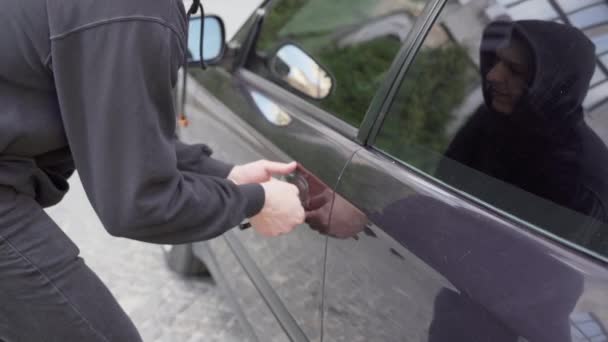 Autólopás tolvaj ellopni autó betörés ajtó bűnügyi munka betörő Hijacks Auto tolvaj fekete maszk kapucnis próbál betörni jármű csavarhúzó Street bűnözés erőszak gengszter rabló autó — Stock videók