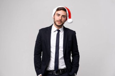 Takım elbiseli yakışıklı beyaz adam ve Noel Baba şapkaları stüdyo dişlerindeki beyaz arka planda duruyor Smilie. Noel havasında portre yapan iş adamını kapatıyoruz. Tatil afişi.