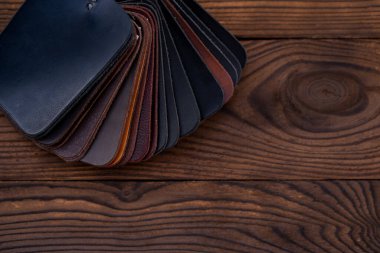 Koyu ahşap masadaki ayakkabılar için deri örnekleri. Mobilya tasarımcısı kıyafetleri.. 