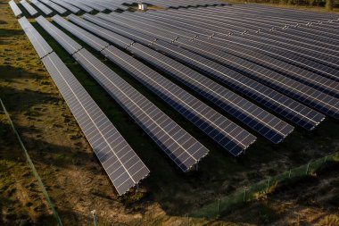 Güneşli bir günde kırsal alanlardaki sıra sıra güneş panellerinin yüksek açılı görüntüsü, temiz enerjiden yararlanmak ve sakin ve açık arazide sürdürülebilir tarım uygulamalarını yansıtmak