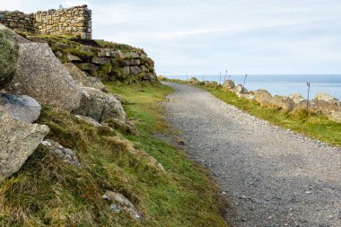 yüksek dağ deniz kıyısında; çakıllı geçit var olduğu bir taş duvar parçası hill yanında; yolun kenarı boyunca büyük kayalar