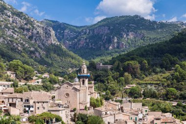 küçük dağ köyü ile bir dağ vadi; arka plan beyaz bulutlar mavi bir gökyüzü üzerinde büyük dağlar