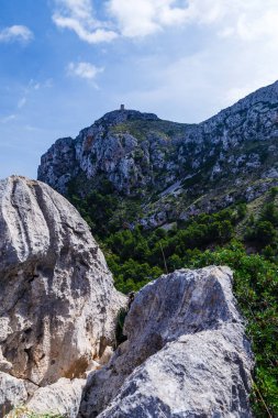 ağaçlar mavi gökyüzü arka plan üzerinde dağlarla; at en üst bir kule ile büyük bir tepe; tepenin eteğinde yeşil orman