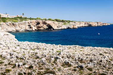 bir nehir karşısında sarp bir kayalık sahil ile yan orada ağaçlar, çeşitli evler turistlere; ön plan boş, kayalık bölgede