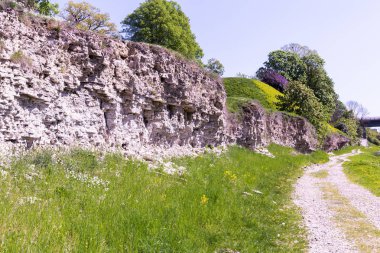 bir tepenin Dolomit kayaları bir boş çakıl yol kenarında açık; Baharda çiçek açan ağaçlar ve çalılar ile bir tepe üzerindedir