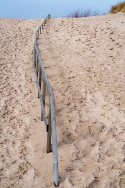 Sahil beyaz, ince kum tepeleri, ahşap çit her iki tarafında kum birçok feet, gökyüzünde mesafe kazlar içinde