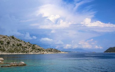 mavi sularda yat manzarası ve mavi gökyüzünde çeşitli dağ manzarası; yaz aylarında seyahat keyfi