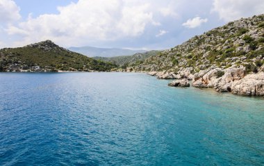 mavi sularda yat manzarası ve mavi gökyüzünde çeşitli dağ manzarası; yaz aylarında seyahat keyfi