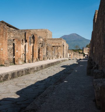 Pompeii, İtalya - 04.28.2025: Sokağın sonundaki Pompeii ve Vesuvius Dağı 'ndaki antik bir caddenin görüntüsü.