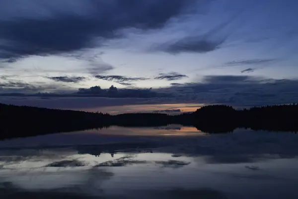 Um belo pôr do sol sobre um lago de floresta com nuvens refletidas na água — Fotografia de Stock