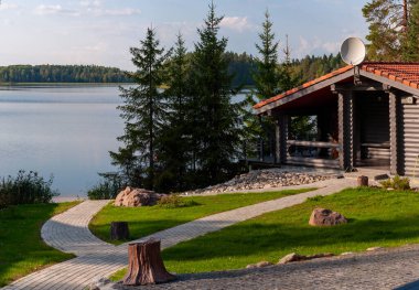 kaldırımlı yolları ve orman gölü kıyısında bir evi olan bir manzara.