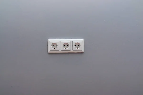灰墙上的白色三重插座 — 图库照片