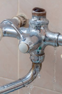 Suyun aktığı banyodaki kırık musluğun yakın çekimi. Su sızıntısı.