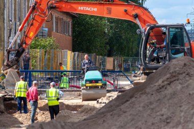 Petrozavodsk, Rusya - 2 Eylül 2019. Bir kazıcı, yol silindiri ve birkaç işçi yol çalışması yapıyor.